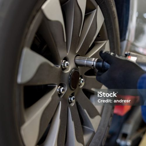 Close-up on a mechanic fixing a flat tire on a car and unscrewing the rim bolts